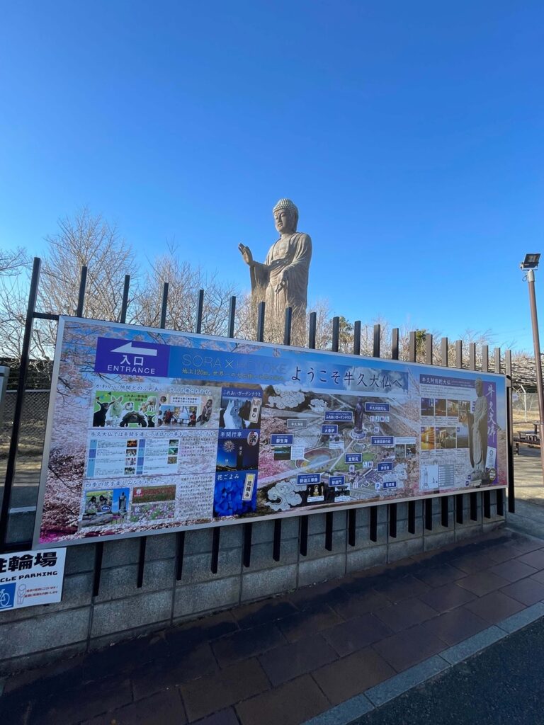 牛久大仏の入口付近に設置された案内看板と、奥にそびえ立つ巨大な大仏