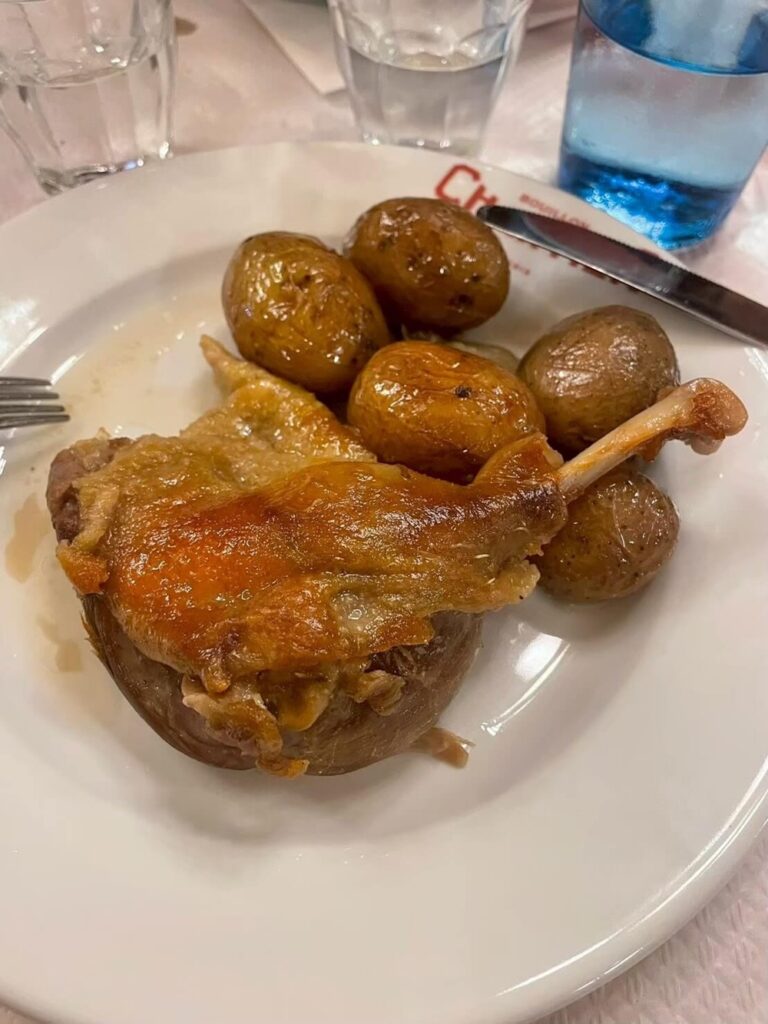 こんがり焼けた鴨のコンフィと、丸ごとのローストポテトが盛られた一皿