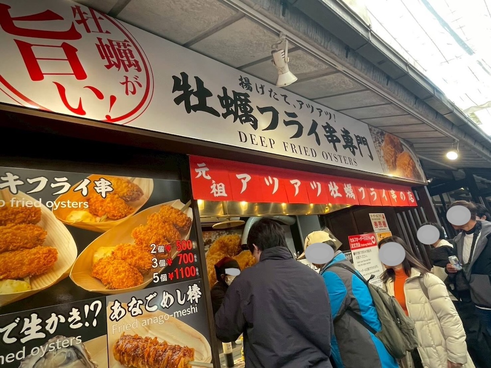 宮島のカキフライ串専門店の外観。揚げたての文字とメニュー看板