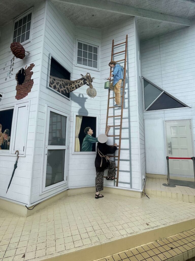 トリックアートピアのトリックアートの館で壁のはしごに登っているように見えるトリックアート